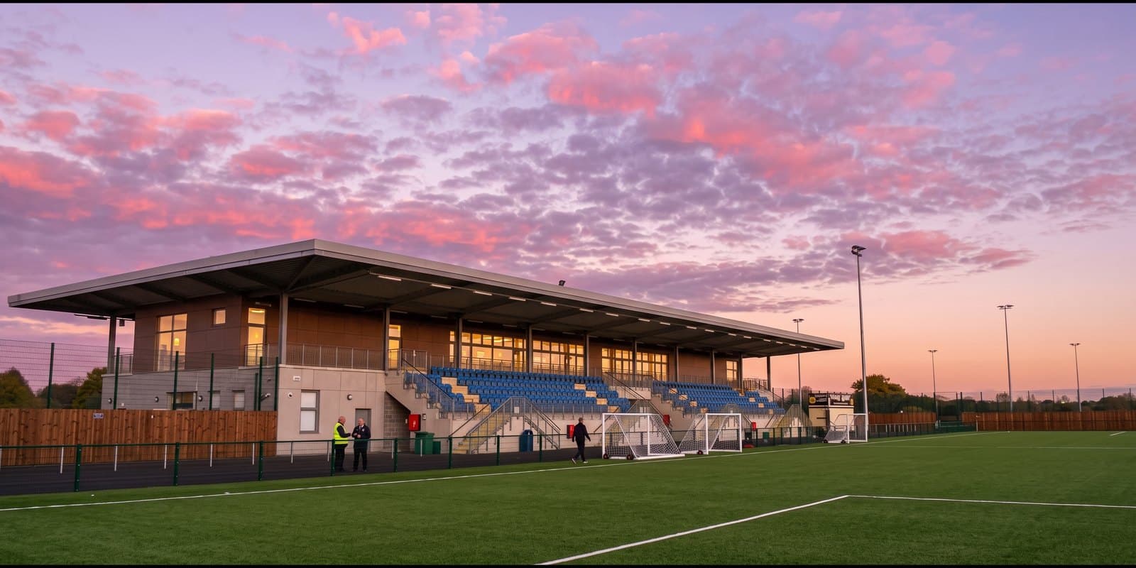 A floodlit clubhouse and pitch at dusk